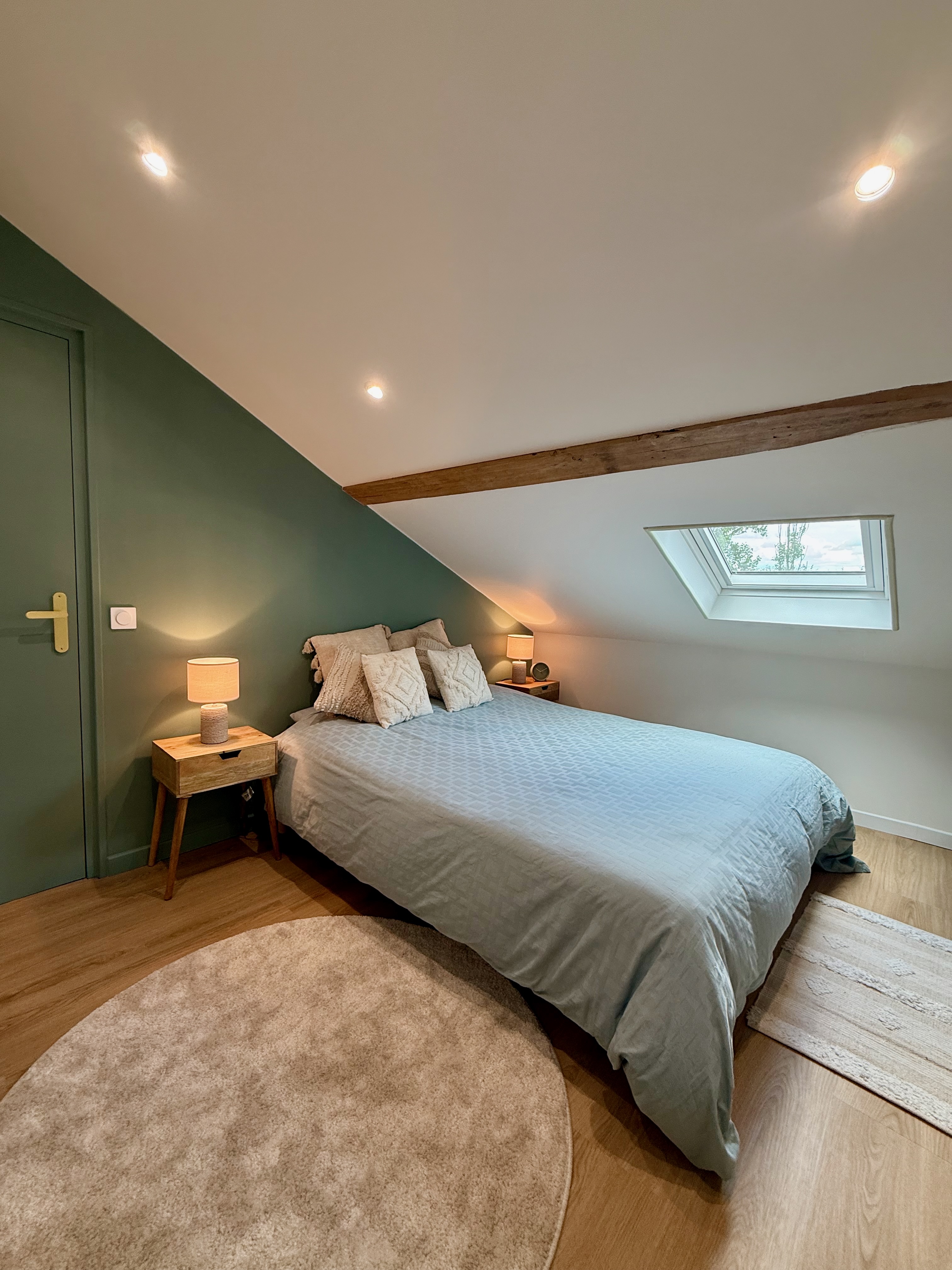Chambre cosy sous les toits avec mur vert sauge et fenêtre de toit