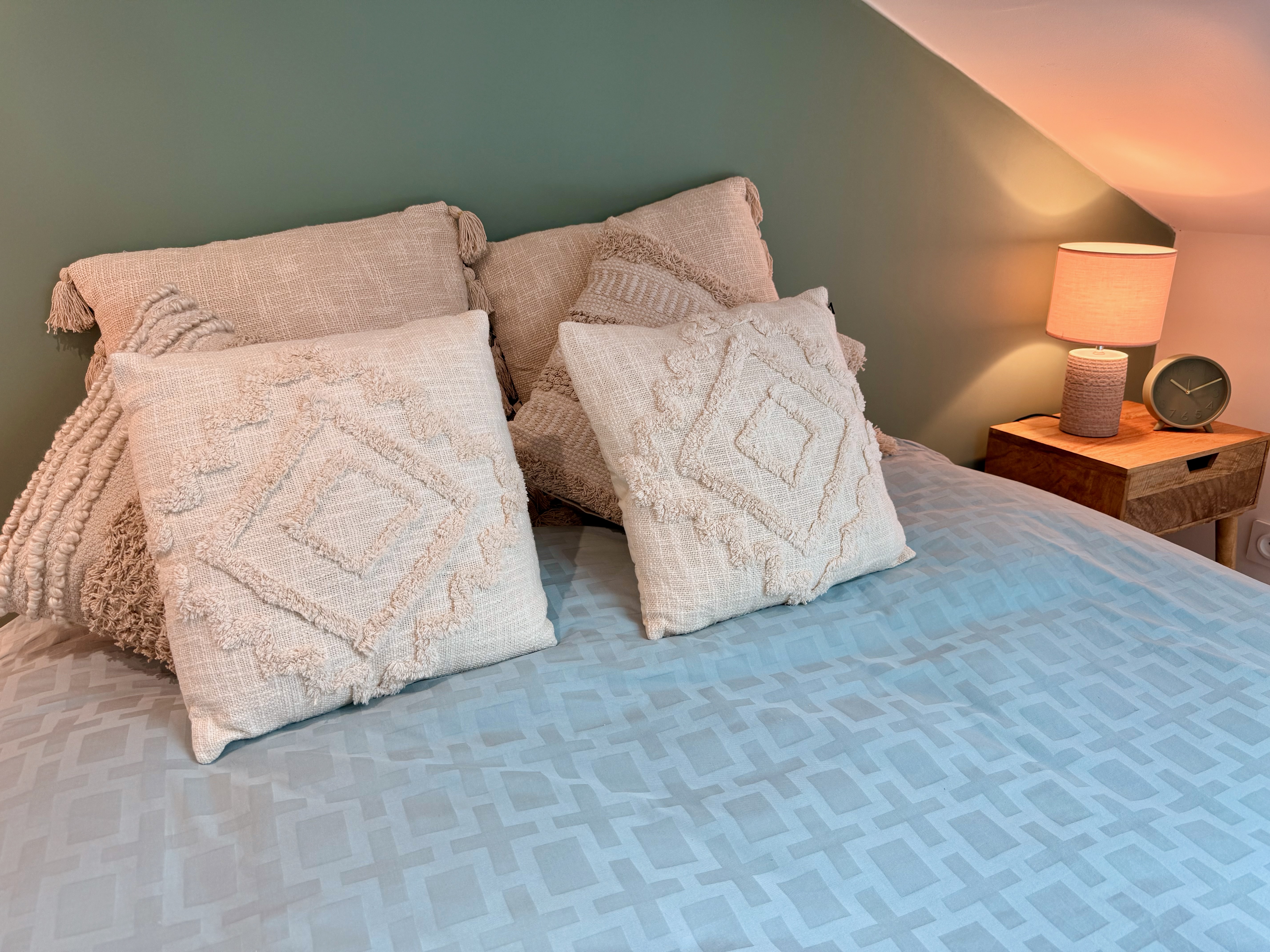 Lit douillet avec coussins en macramé et lampe de chevet